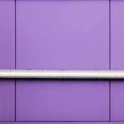 Low angle view of illuminated lighting equipment on purple wall