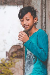 Teenage boy standing against wall