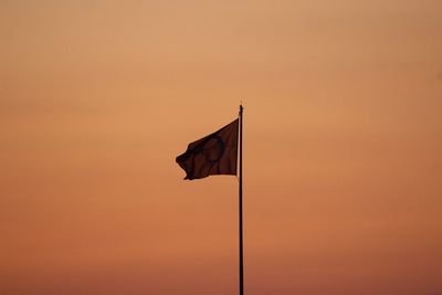 Low angle view of flag against orange sky