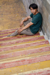 Portrait of young woman sitting on footpath