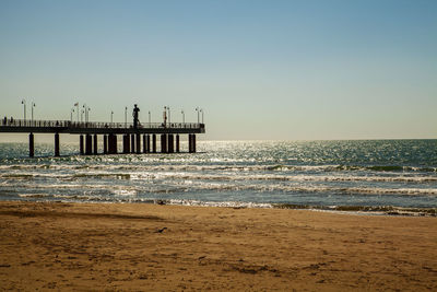 Pier over sea against clear sky during sunset