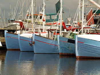 Boats moored at harbor against sky