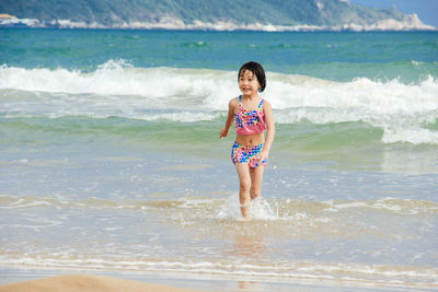 Full length of girl walking in water at beach against sea