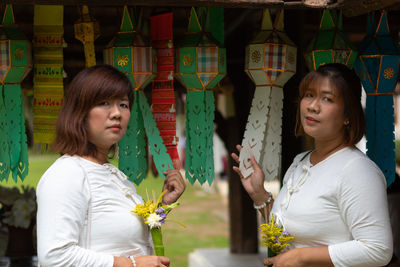 Portrait of sisters with bouquets standing by lanterns