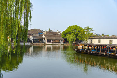 Buildings by river against clear sky