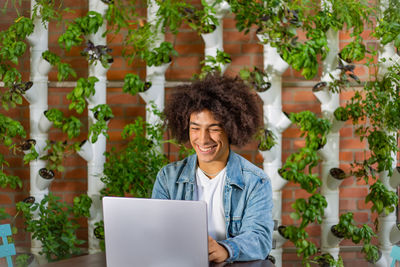 Portrait of young woman using digital tablet while standing against trees