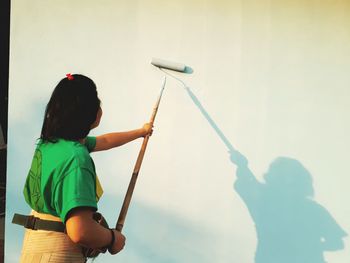 Rear view of woman painting wall