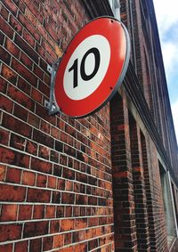 Low angle view of road sign against brick wall