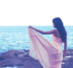 Young woman looking at sea against sky