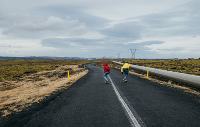 Rear view of people on road against sky