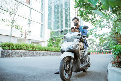 Man riding motor scooter on road