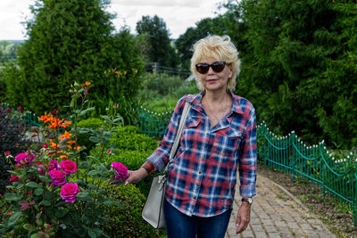 Mature woman with sunglasses standing by plants