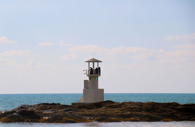 Lighthouse by sea against sky