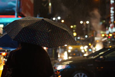 Rear view of woman on wet street at night