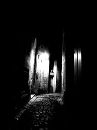 Empty alley amidst buildings in city at night