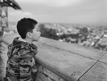 Side view of boy looking away against sky