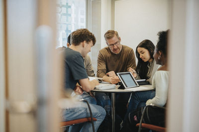 Mature male professor explaining students at table in university