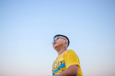 Boy looking away against clear sky