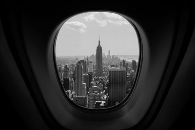 Buildings against sky seen through airplane window