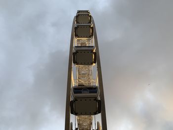 Low angle view of ferris wheel against cloudy sky