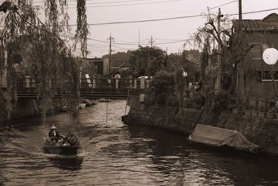 Boats in canal by city against sky