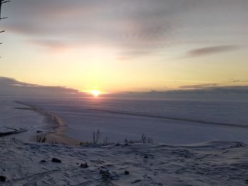 Scenic view of snow covered land against sky during sunset