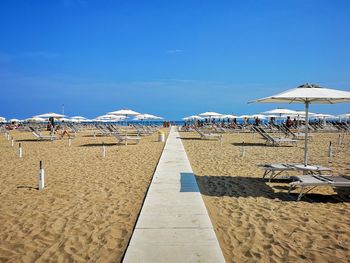 Parasols on beach against blue sky