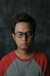 Portrait of young man wearing eyeglasses against black background