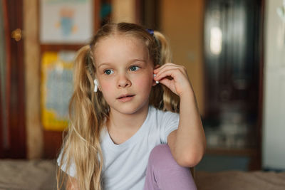 Portrait of a smiling child, listening to music in white headphones, dancing, fooling around at home