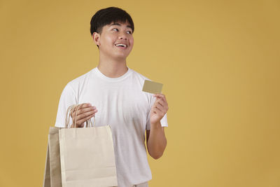 Boy looking away while standing against yellow background