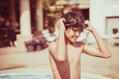 Portrait of shirtless boy wearing sunglasses standing outdoors