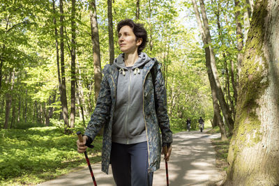 Portrait beautiful 36 yo woman trekking with sticks, happy caucasian 36 yo hiking female, nordic