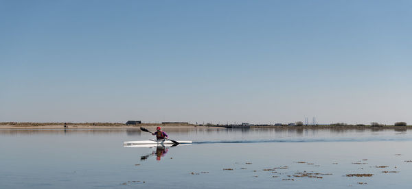 Man on lake against clear sky