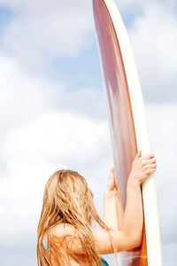 Rear view of woman holding umbrella against sky