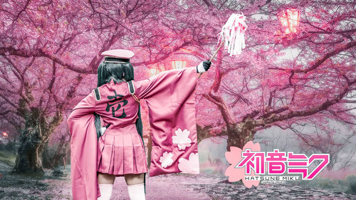 Low angle view of woman standing by pink cherry blossom tree