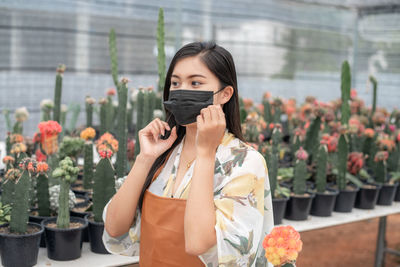 Portrait of beautiful woman standing against pink flowering plants