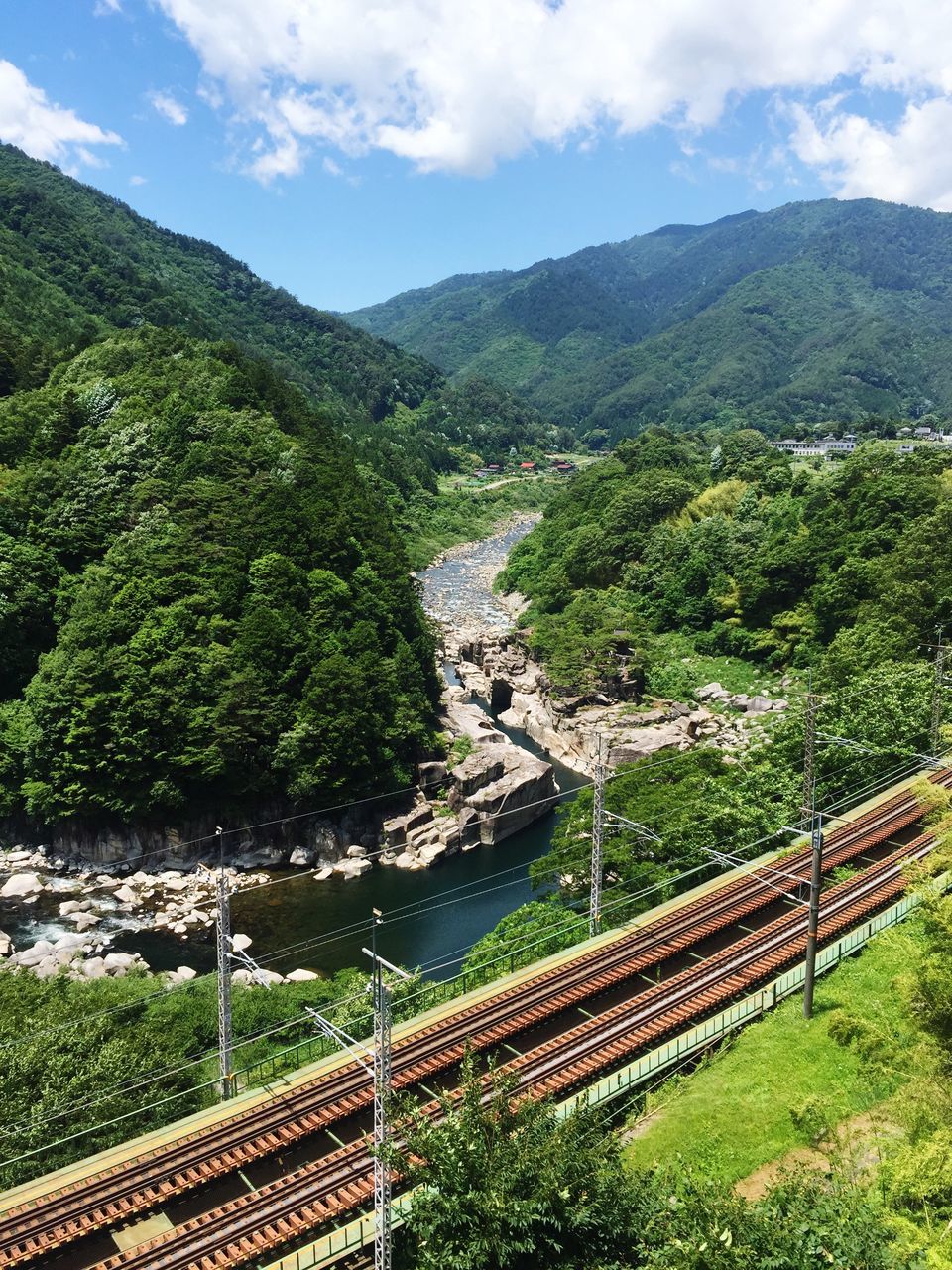 tree, plant, transportation, mountain, rail transportation, nature, sky, scenics - nature, beauty in nature, high angle view, cloud - sky, connection, no people, architecture, railroad track, bridge, day, built structure, green color, track, bridge - man made structure, mountain range, outdoors