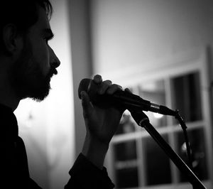 Side view of man singing in illuminated room