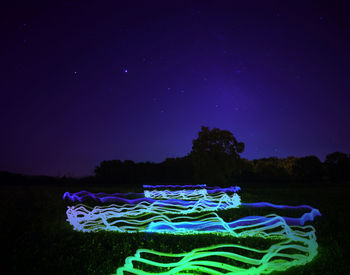 Digital composite image of illuminated light trails against sky