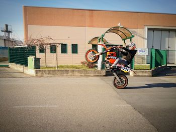 Man riding bicycle on road against building