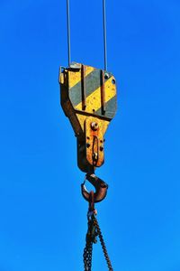 Low angle view of crane against clear blue sky