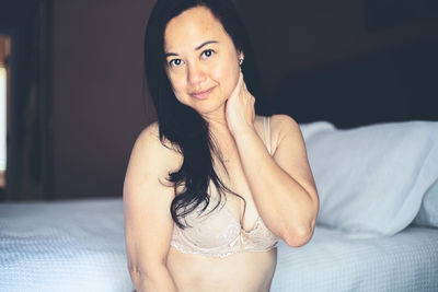 Portrait of smiling woman wearing lingerie sitting on bed