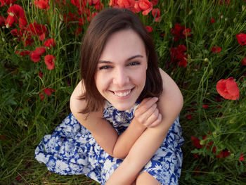 Portrait of young woman standing amidst plants on field