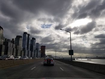 Vehicles on road in city against sky