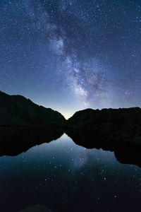 Scenic view of lake and mountains against sky at night