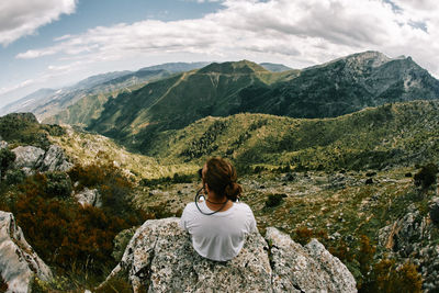 Rear view of man looking at mountains against sky