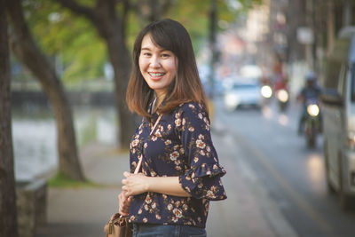 Portrait of smiling woman standing on road