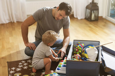 Father and baby boy playing toys on floor at home