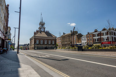 Road by buildings against sky in city