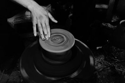 Cropped hand shaping pottery in darkroom